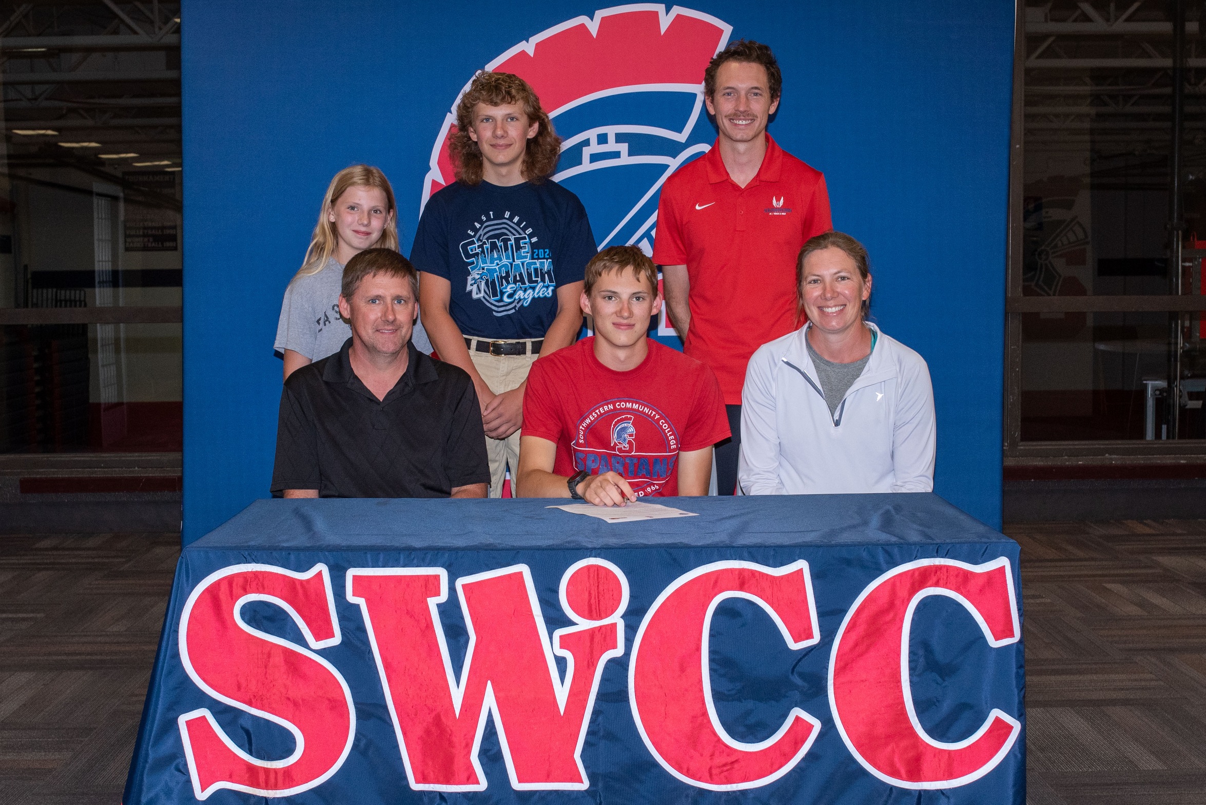 Jacob Driskill, in front center, signs his National Letter of Intent to run cross country and track at SWCC. He is joined in front by parents Jason and Ronda Driskill. In back, from left, are sister Brecklynn Driskill, brother Brock Driskill, and SWCC Director of Cross Country/Track & Field Scott Vicker.