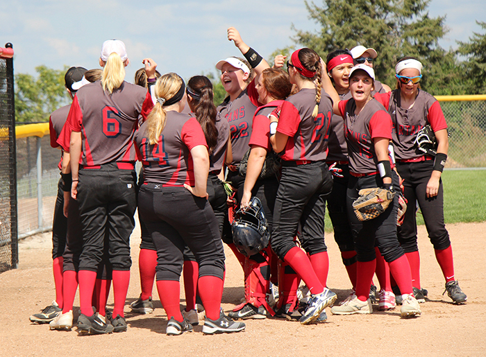 Spartan softball team in huddle on field during softball game.